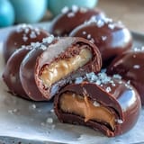 Decadent dark chocolate peanut butter eggs topped with flaky sea salt, offering a sweet-salty flavor combination in a festive Easter treat.