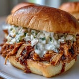Tender pulled chicken atop soft buns, generously drizzled with creamy white sauce.