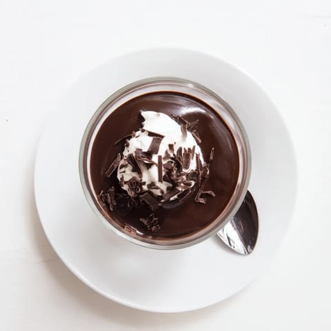 Chilled chocolate pudding in clear glasses topped with whipped cream and chocolate shavings