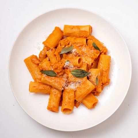 Fork twirls vibrant rigatoni pasta coated in a mildly spicy, velvety Italian-American sauce.  