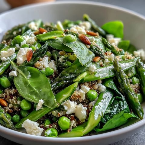 Vibrant Spring Green Bowl topped with fresh peas, crisp asparagus, and sautéed spinach in a zesty lemon dressing.