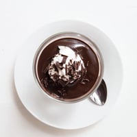 Chilled chocolate pudding in clear glasses topped with whipped cream and chocolate shavings