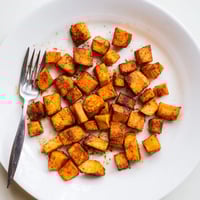 Roasted Sweet Potatoes with golden caramelized edges and warm spices on a baking sheet.