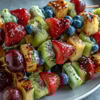 Rainbow Fruit Skewers with Honey Dip, a vibrant and refreshing summer snack, arranged in a colorful pattern with juicy strawberries, pineapple, and grapes.